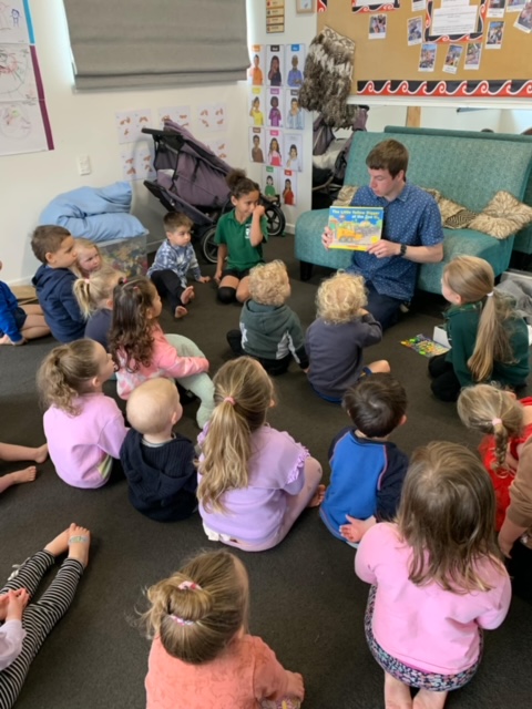 A teacher reading to a group of young students